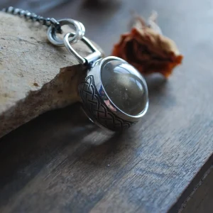 Pendentif sphère de quartz serti d'une bande d'argent gravée d'un motif celtique